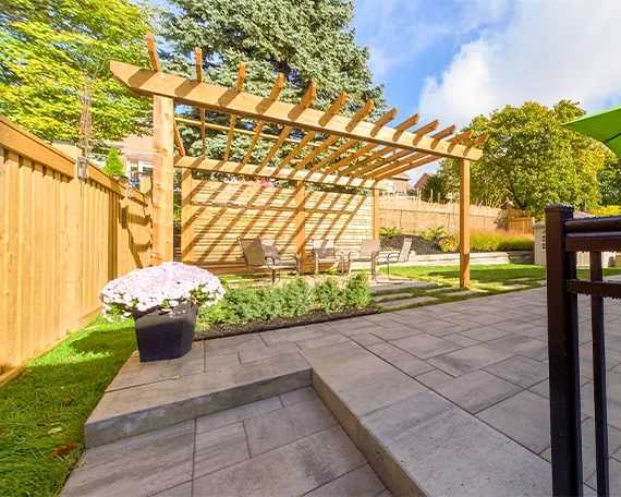 A stone patio and steps beneath a wood pergola
