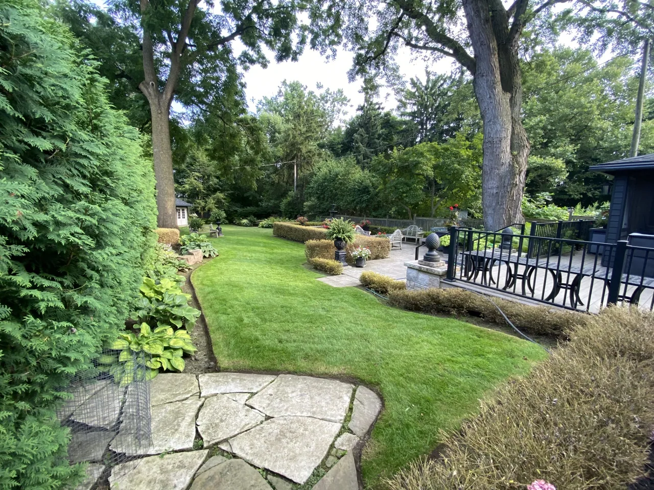 A landscaped lawn with curved garden beds and mature trees